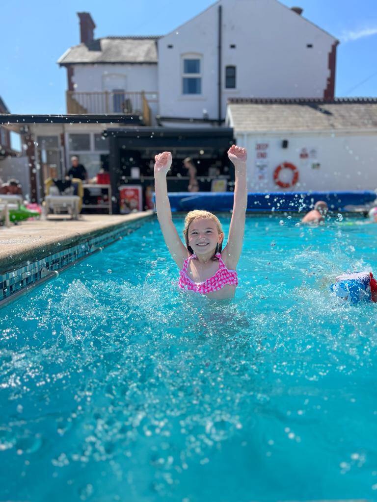 A young guest splashing in the outdoor pool at the Doric Hotel